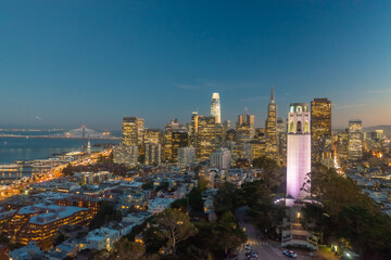 Fototapeta na wymiar Nighttime aerial view of the San Francisco skyline with Coit Tower prominent in the frame. Bay Bridge in the background.