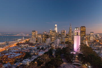 Obraz premium Nighttime aerial view of the San Francisco skyline with Coit Tower prominent in the frame. Bay Bridge in the background.