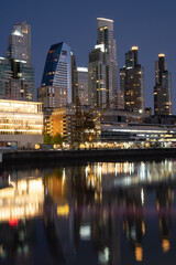 Naklejka premium Puerto Madero, Buenos Aires buildings reflected in the water, night in a luxurious neighborhood. vertical picture