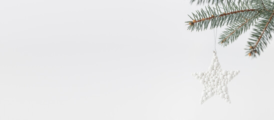 White star decoration on Christmas tree branch. Simple, minimalistic, monochromatic holiday decor.