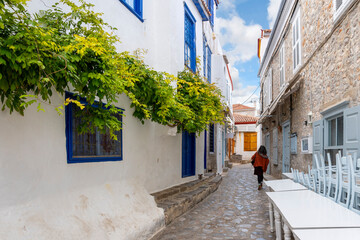 A woman walks through a colorful narrow alley on the island of Hydra, one of the Saronic islands of Southern Greece.
