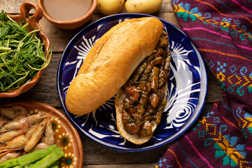 Mexican romeritos sandwich with mole sauce and shrimp on a wooden background
