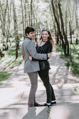 Fototapeta premium girl laughing happily standing next to beloved boyfriend in spring in park. guy and girl bonding in love. Happy couple smiling having fun relaxing outdoors. Careless young lovers enjoying romantic