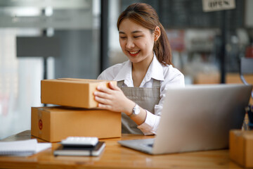 Fototapeta premium Portrait of Starting small young businesses SME owners female entrepreneurs working on receipt box and check online orders to prepare to pack the boxes, sell to customers, SME business ideas online.