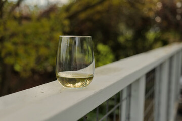 Glass of white wine on a white railing outside
