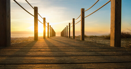 Wooden walkway on beach at sunset . Path leading to ocean.