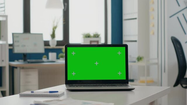 Close up of laptop with green screen in empty office. Nobody at desk with isolated background and mock up template on chroma key display. Device with blank mock-up copy space screen.