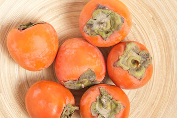 Fruits of persimmon fruit in plate, top view.