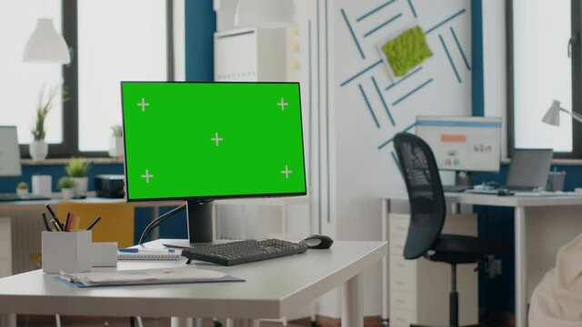 Empty office with green screen on computer display. Nobody in space with isolated chroma key template and mock up background on monitor at desk. Mockup copy space screen on gadget.