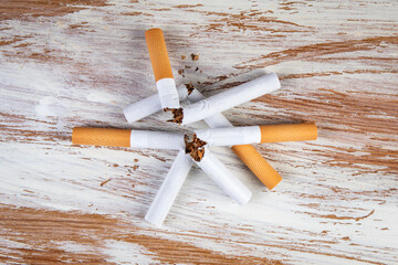 Stack of broken cigarettes on a white painted wooden background