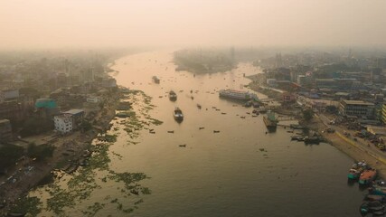Aerial timelapse of busy river port with cargo ships beside urban city, air pollution concept