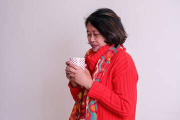 Woman in red warm clothes holding cup of hot drink for Christmas