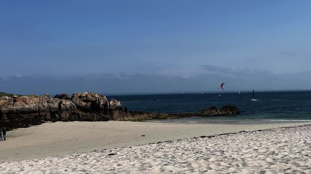 Panning view of white beach with kitesurfer in the sea. Ile Saint-Nicolas. Concarneau. France