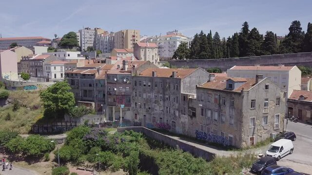 Aerial shot of an old dilapidated apartment building in Lisbon, Portugal. Drone is flying slowly backwards.