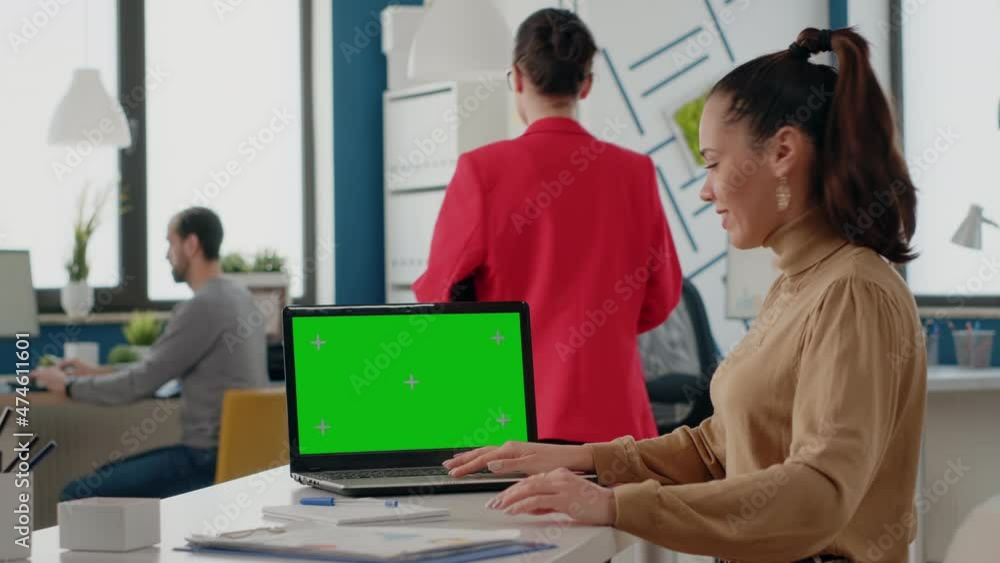Poster business woman using laptop with green screen in office. company worker looking at chroma key with i
