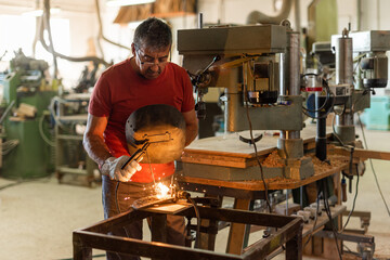 Person in red T-shirt welding in a manufacturing plant