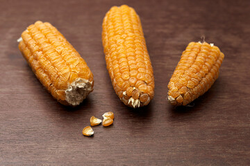 A few ears of corn are lying on a wooden table