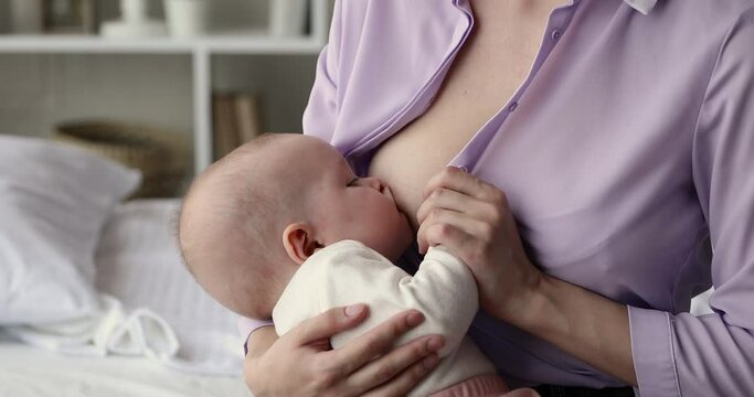 Eating mother milk. Close up shot of calm little kid infant breastfeeding on mom hands at home. Lactating woman young mom choosing natural breast feeding nursing hungry baby child having good appetite