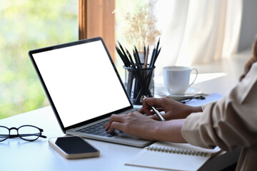 Cropped image of businesswoman working with computer laptop in bright office.