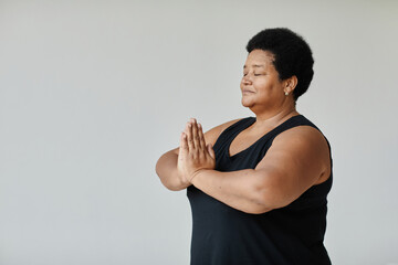 Minimal side view portrait of black senior woman meditating with eyes closed while doing yoga indoors, copy space - obrazy, fototapety, plakaty