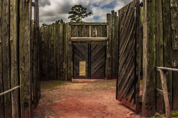 Heavy double doors and palisades reconstructing the fence line which once enclosed the infamous Andersonville Civil War POW camp in the state of Georgia with selective focus on the foreground gate