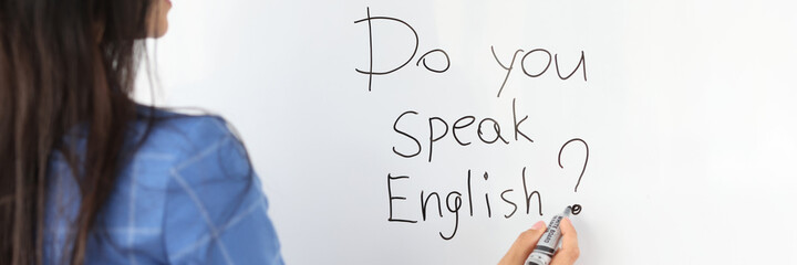 Woman teacher writes with marker do you speak english on white board