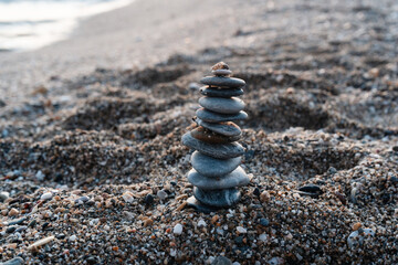 Fototapeta na wymiar A pyramid of pebbles on the beach in the evening on a summer beatiful day. Real nature backround