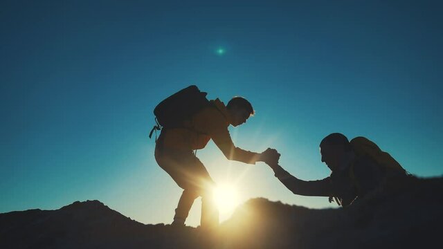 help team concept. team silhouette of two climber stretching a helping hand to a friend. business teamwork success concept. silhouette business travel tourists pull sunlight a helping hand
