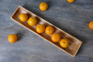 Christmas or New Year's still life of tangerines lying on wooden rectangular plate with spruce branches