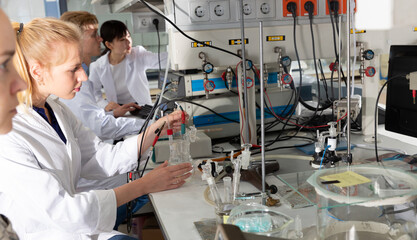 Portrait of intelligent female student working with her coursemates in college laboratory