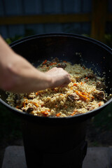 Cooking pilaf outdoors in a cauldron on an open fire , Asian cuisine