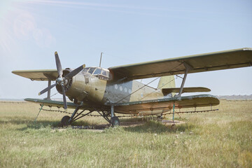 Naklejka premium An old Soviet AN 2 aircraft of protective color stands at the airfield in a green field