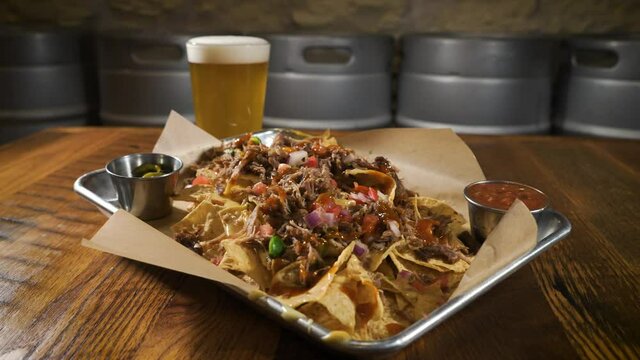 Brewery carnitas nachos slathered in queso paired with a light beer, slider 4K