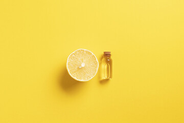 Serum with vitamin C. Lemon essential oil. Great fermented ingredient.Glass bottle with a pipette, half a lemon on yellow background. Health and beauty concept. Organic natural cosmetics.