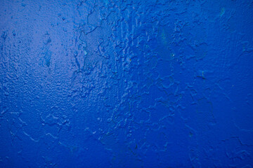 Cracked texture of blue paint on metal and brick.