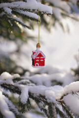 A deer figurine and toy houses stand on a table in the snow.