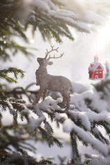 A deer figurine and toy houses stand on a table in the snow.