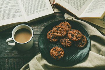 Top view of books with cup of coffee and chocolate cookies. Selective focus