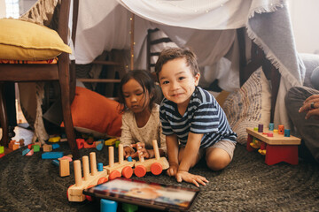 Cheerful little boy playing with his sister at home