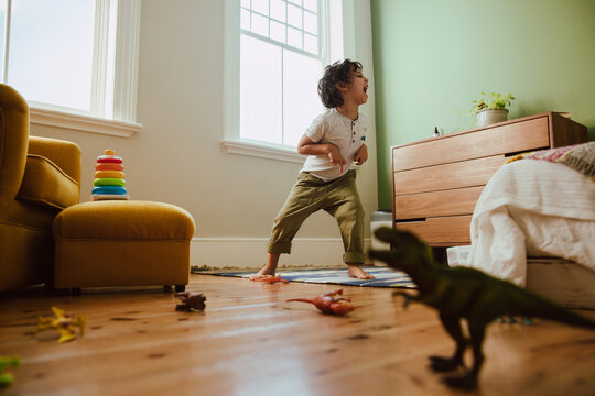 Playful young boy mimicking a t-rex dinosaur at home