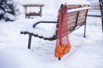 Tangerines in a bag are hanging on an old door.