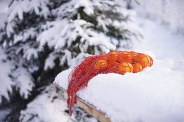 Tangerines in a bag are hanging on an old door.