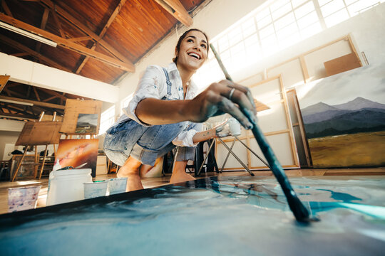 Innovative young artist painting on a large canvas