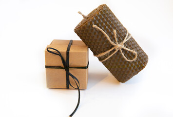 Gift Box Wrapped in Craft Paper with Black Ribbon and Bow on White Background and Brown Wax Candle Gifts for men concept. Father's Day Card, Holiday Decor. Copy space