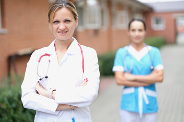 Woman doctor and nurse stand near the clinic
