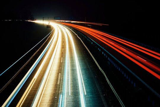 Moving cars at night on highway, long exposure. Motion blur effect of light trails. Fast speet traffic