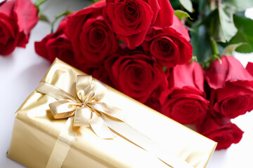Gift wrapped in gold and a bouquet of red roses