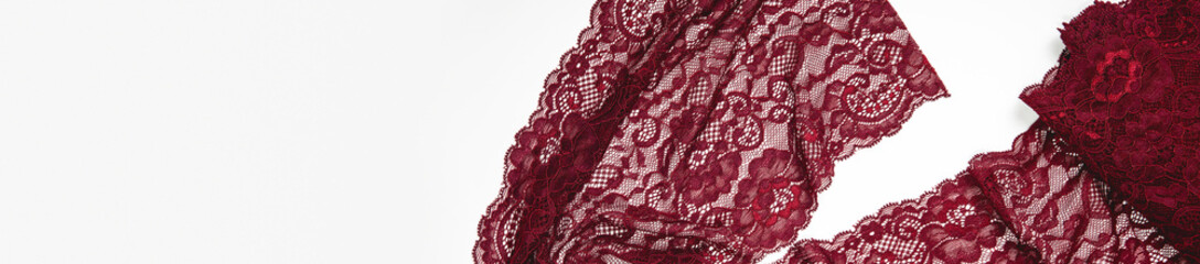 Creative sewing background, top view. Red, burgundy lace fabric. luxury cloth or liquid wave