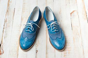 Blue imitation leather shoes laced with white laces. Close-up shot.