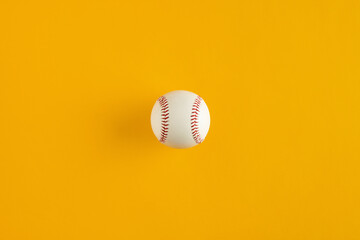 Baseball ball on yellow background with copy space.